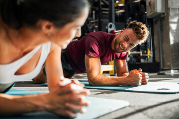 Young Couple Performing Plank Exercises Together in Modern Gym Setting