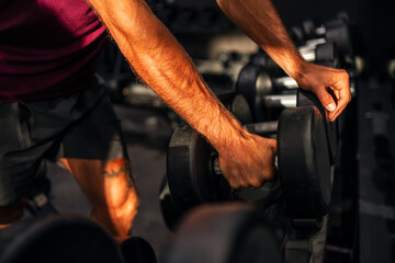 Close-Up of Hands Lifting Dumbbells in a Gym Setting