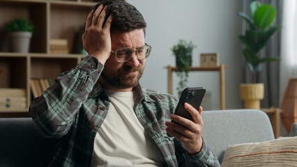 Caucasian man male guy supporter gamer playing video game smartphone at home worried looking at mobile phone online bet gambling sport match betting casino waiting sad disappointed lost failure looser