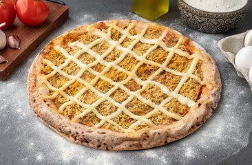 Chicken and Catupiry cream cheese pizza over stone background with flour, tomatoes and eggs