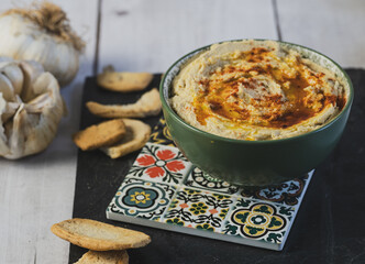 Beautiful bowl of hummus, traditional Middle Eastern vegetarian dish based on chickpeas and seasoned with olive oil and paprika