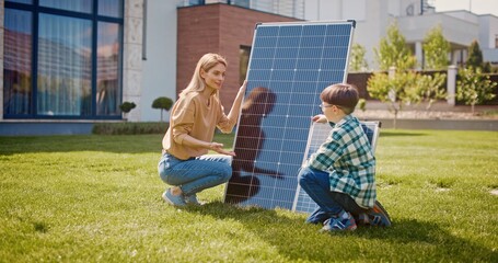 Fototapeta premium Mother and son talking about importance of preserving planet's ecosystem. Mother and son near solar panels. Woman and boy on lawn at background of house. Conversion of sunlight into electricity.