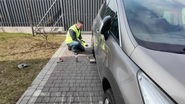 A guy changes tire on street to summer tire in nature