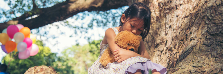 Banner Sad girl hug teddy bear sit sadness alone in green park. Banner Lonely girl feeling sad cry...