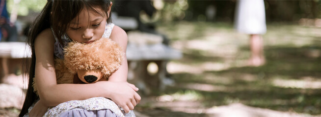 Banner Sad girl hug teddy bear sit sadness alone in green park. Banner Lonely girl feeling sad cry...