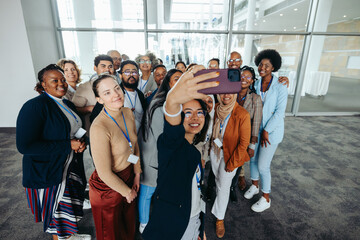 Corporate team of diverse colleagues taking a group selfie at the office