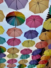 Colorful Umbrellas Hanging in the Sky – Urban Art Installation Against Blue Sky. Perfect for themes of creativity, travel, summer, happiness, and street art.