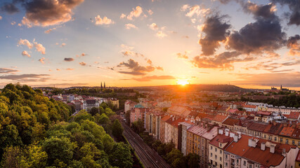 Panoramic sunset over Prague with red rooftops and green trees