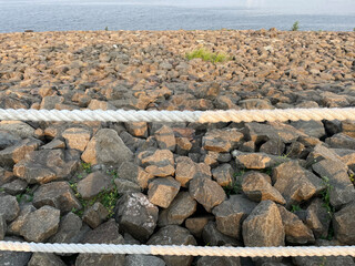 Obraz premium Beach with rock fragments and blue sky background with rope barrier