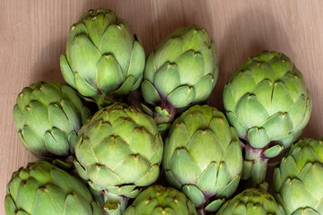 Fototapeta premium A detailed view of multiple green artichokes laid out on a table showcasing their texture. The image highlights the fresh, natural appearance of these vegetables, ideal for culinary, food, diet