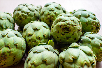 Fototapeta premium A detailed view of multiple green artichokes laid out on a table showcasing their texture. The image highlights the fresh, natural appearance of these vegetables, ideal for culinary, food, diet