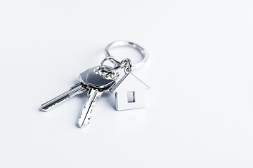 Silver house-shaped keychain with keys on a white background.