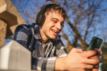 young man student stand in nature on sunny day and listen music