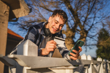 man stand outdoor use mobile phone and credit card for online shopping