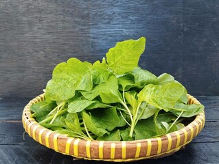 Fresh spinach on basket with wooden table background 
