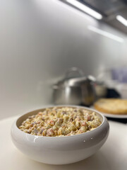 Traditional Olivier Salad Served in White Ceramic Bowl on Modern Kitchen Counter