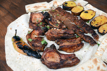 Barbecue with grilled meat and shish kebab. Grilled lamb ribs, kebab, potatoes and pita bread on wooden board. Restaurant food, pork barbecue, bbq.
