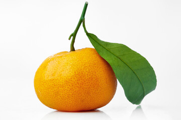 Close up Shot of a Bright Small Orange Showing Detailed Texture and Fresh Green Leaf on a White Background