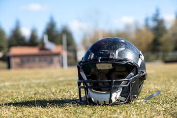worn helmet, worn american football helmet and football field, grass and white lines, black helmet
