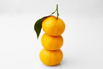 Close up Texture of Stacked Small Oranges With Green Leaves Highlighting Freshness and Vibrant Color on White and Isolated Background