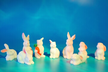 Toy white hares on a blue background. Animal figurines.