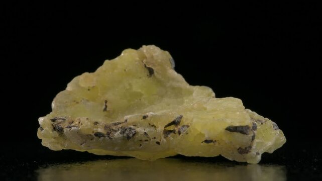 Yellow Brucite (magnesium hydroxide -  Mg(OH)2 ) rotating against a black background