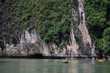 Vietnamese people and foreign travelers rowing paddle canoe boat travel visit cave and respect small shrine in Halong lake or Ha Long Bay UNESCO World Natural Heritage Site in Hanoi, Vietnam