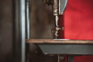 Closeup of the needle and mechanism of a vintage sewing machine with a blurred background.