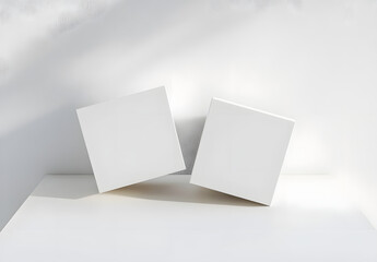Fototapeta premium Two blank white square boxes positioned on a clean surface for product mockups or design presentations&nbsp;