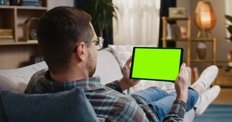 Back vision of man holding tablet with chroma key screen. Close up view of man looking at tablet...