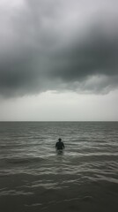 Person stands solitary in wavy, gray water under a stormy, cloudy sky. Mood is somber and reflective