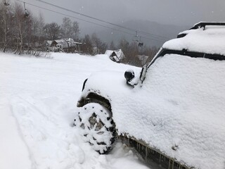 Snow covered off-road vehicle SUV car parked outdoor on a winter ski slope
