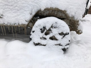 Rear wheel of a snow covered off-road vehicle SUV car parked outdoor on a winter ski slope
