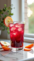 Fototapeta premium Refreshing iced red juice with apple slices on marble counter in sunlit kitchen