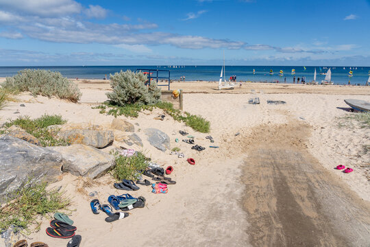 Footwear and sandals scattered along a walking track onto a sandy beach