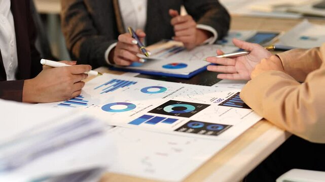 Business team analyzing financial charts and graphs during a meeting, pointing at statistics and discussing data, collaborating on business strategies and making decisions - Powered by Adobe