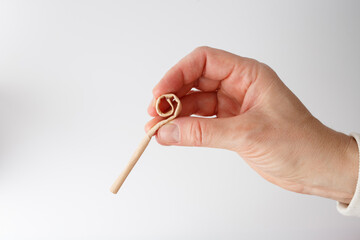 a step in a creative craft process. It features a hand holding a tightly rolled spiral of paper,...