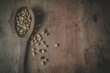 Pine Nuts on a Wooden Spoon Tiny pine nuts spilling from a wooden spoon onto a rustic kitchen surface