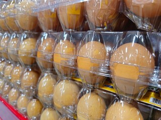 Chicken eggs in a transparent box being sold at a market.