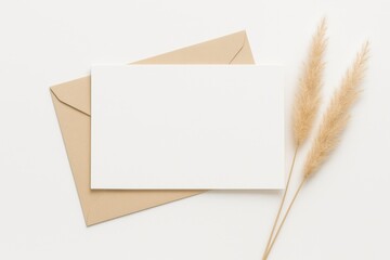 Elegant stationery mockup featuring a blank card, envelope and dried grass on a white background.
