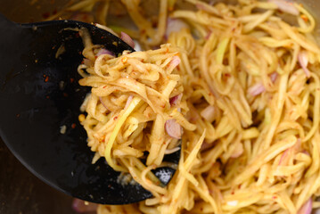 Spicy mango salad mixing in bowl, Thai food