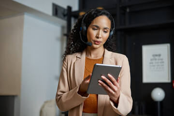 Professional Receptionist Using a Digital Tablet While Assisting Guests in a Modern Hotel Lobby