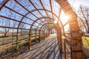 A wooden archway with a sun shining through it