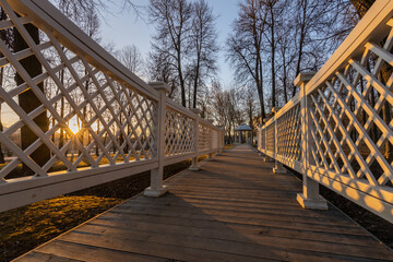A wooden walkway with a lattice fence and a bench