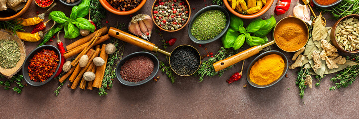 An elegant arrangement of spices and herbs in vivid colors, set against a brown surface,...