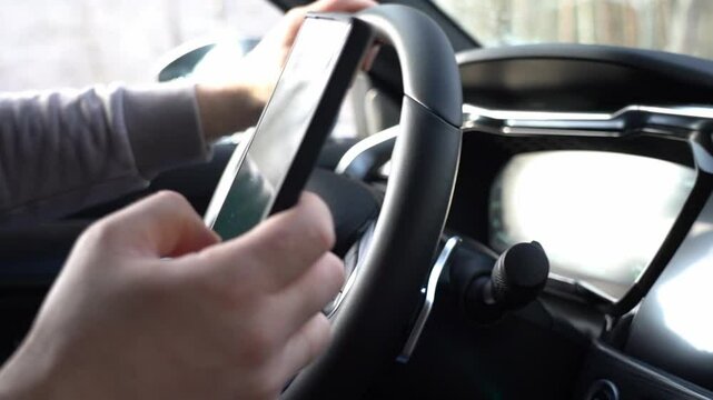 A person is driving a car and looking at their phone. Scene is somewhat tense, as the driver is distracted by their phone while operating a vehicle