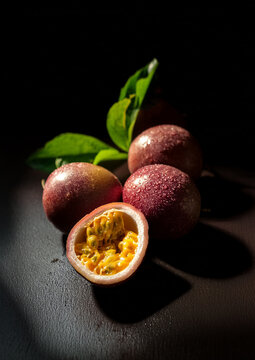 Maracuja / Passionsfrucht ganze Fr&uuml;chte und eine H&auml;lfte aufgeschnitten,  im Chiaroscuro Stil
