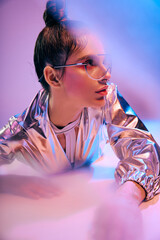 Stylish woman in holographic attire captivates with vibrant energy in a futuristic setting