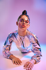 Stylish woman showcases holographic fashion in a modern vibrant setting during daytime