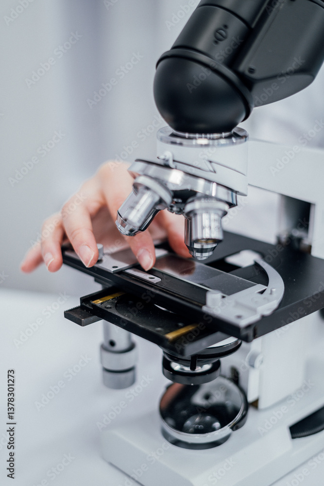 Poster A closeup view microscopes slide stage being carefully adjusted researcher. image highlights precision attention to detail required in laboratory settings, focusing interaction between hand and lenses